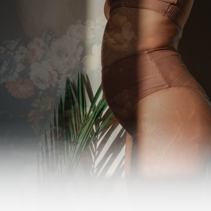 A close-up view of a person's torso wearing brown shapewear against a blurred floral background.