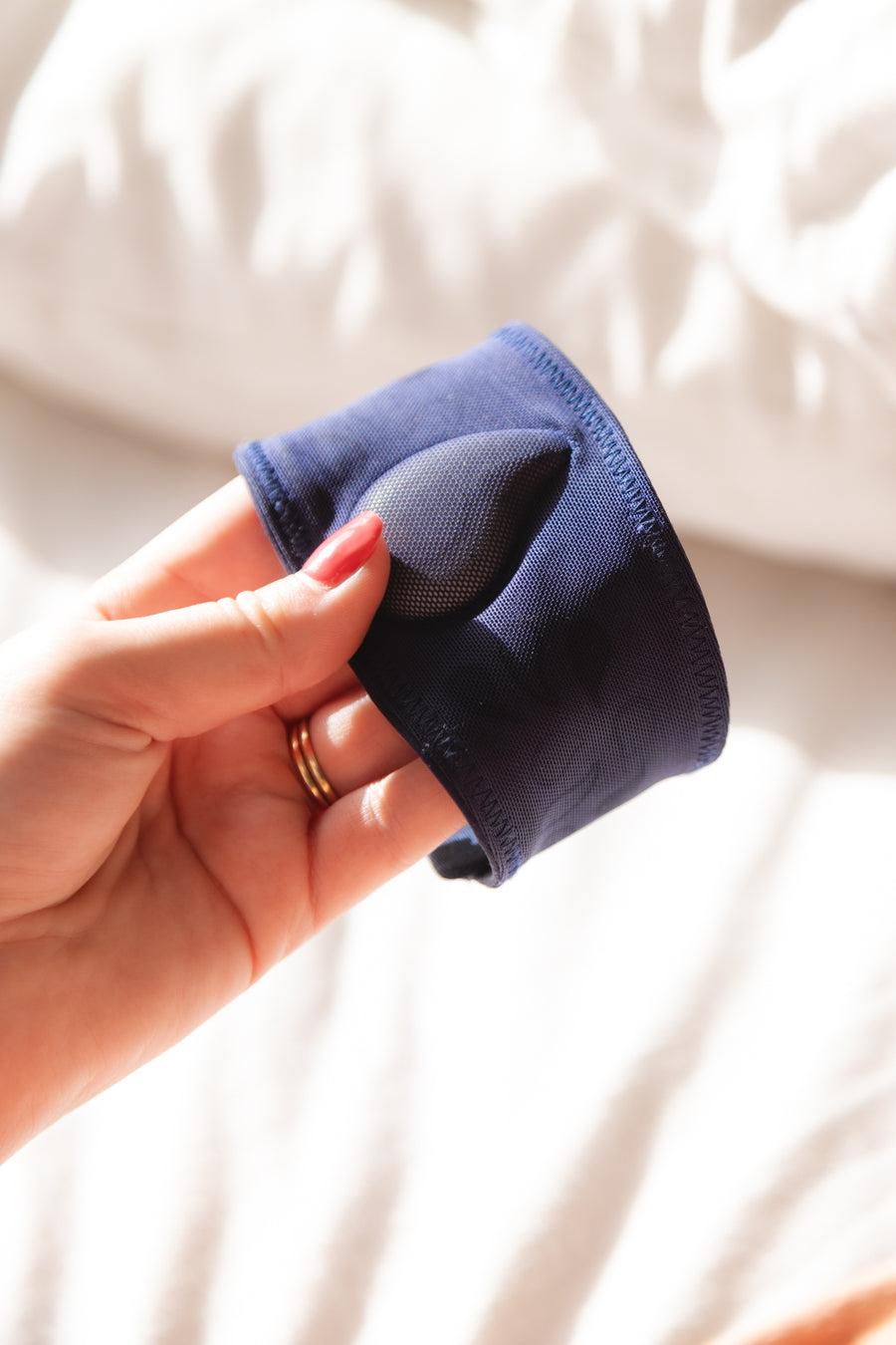 A hand holding a folded blue microfibre cloth against a light background.