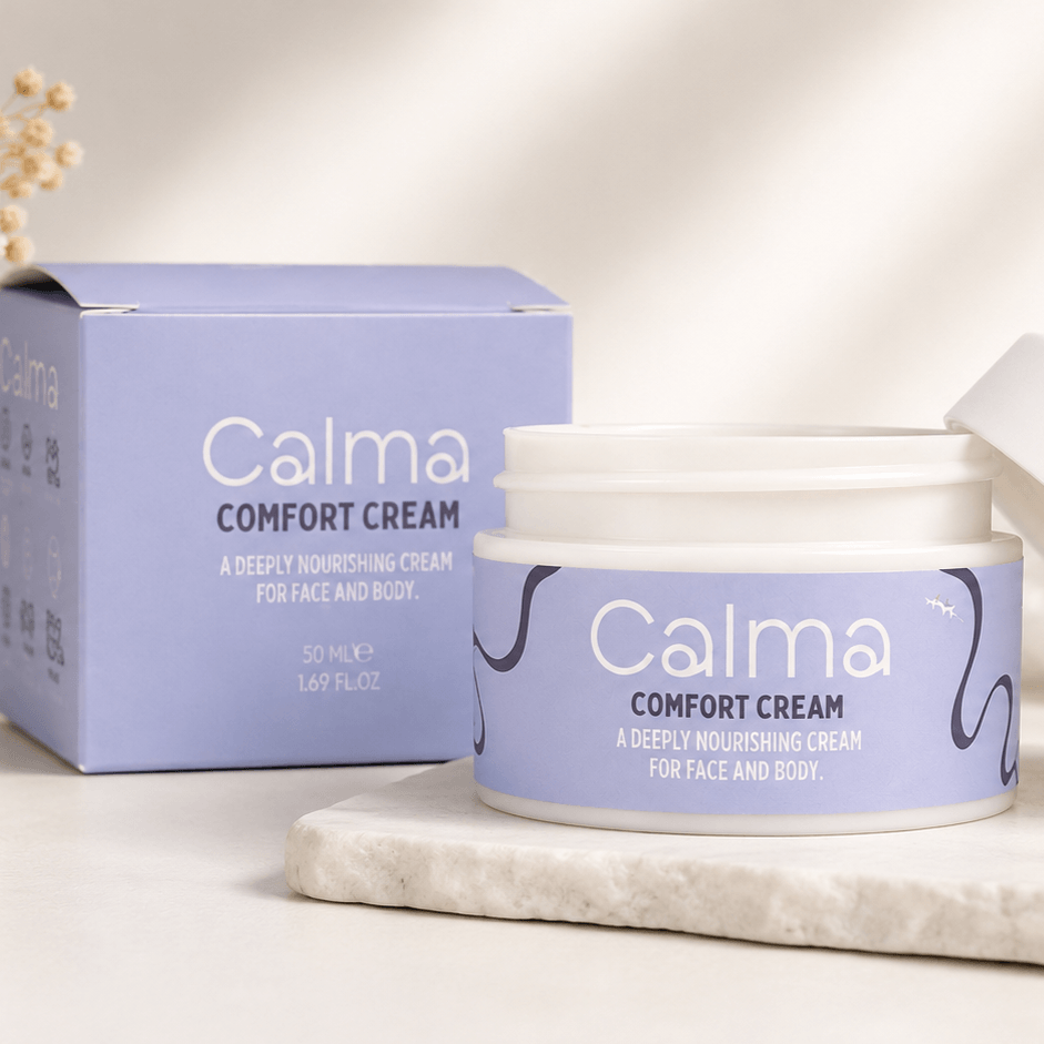 A jar of Calma Comfort Cream and its matching lavender box, styled on a light marble slab against a warm, sunlit neutral background.