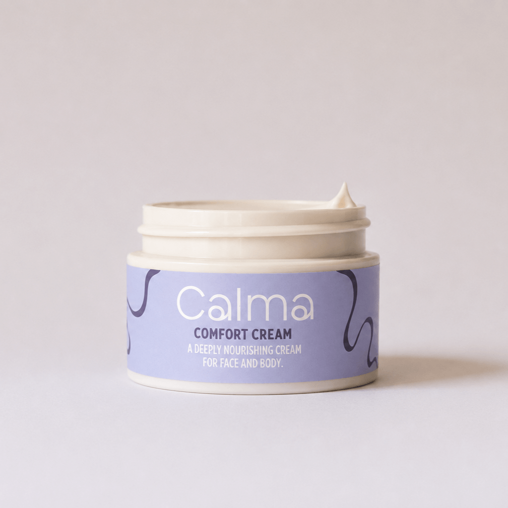An open jar of Calma Comfort Cream showing a thick cream inside, set against a plain light gray background.