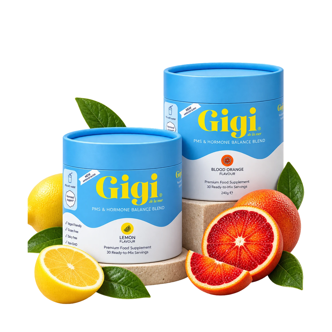 Two blue and white cylindrical supplement containers from Gigi Health, one lemon-flavored and one blood orange-flavored, styled with fresh lemons and blood oranges on a white background.