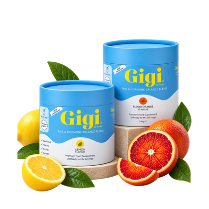 Two blue and white cylindrical supplement containers from Gigi Health, one lemon-flavored and one blood orange-flavored, styled with fresh lemons and blood oranges on a white background.