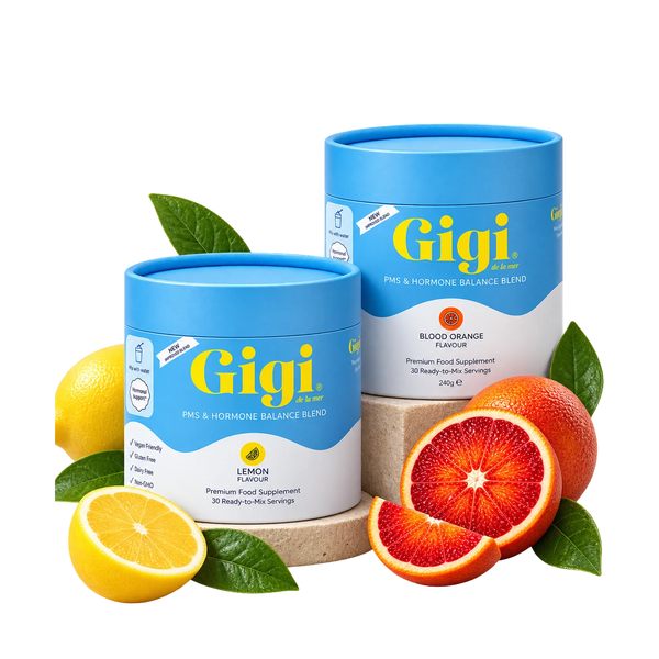 Two blue and white cylindrical supplement containers from Gigi Health, one lemon-flavored and one blood orange-flavored, styled with fresh lemons and blood oranges on a white background.