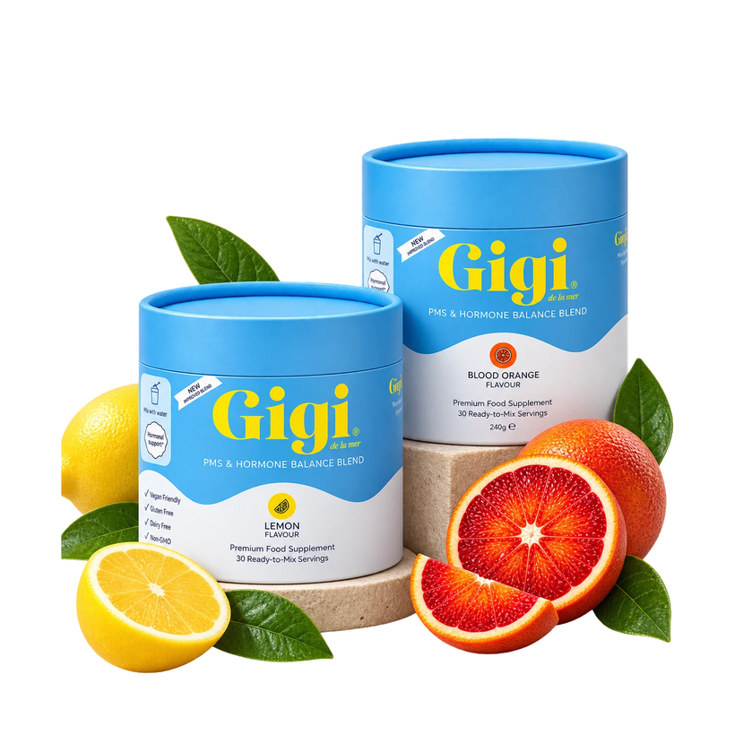 Two blue and white cylindrical supplement containers from Gigi Health, one lemon-flavored and one blood orange-flavored, styled with fresh lemons and blood oranges on a white background.