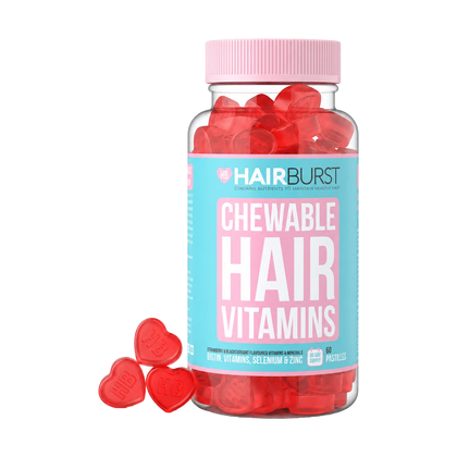 A bottle of HAIRBURST Chewable Hair Vitamins filled with red heart-shaped gummies, with three red heart gummies placed in front on a clean white background.