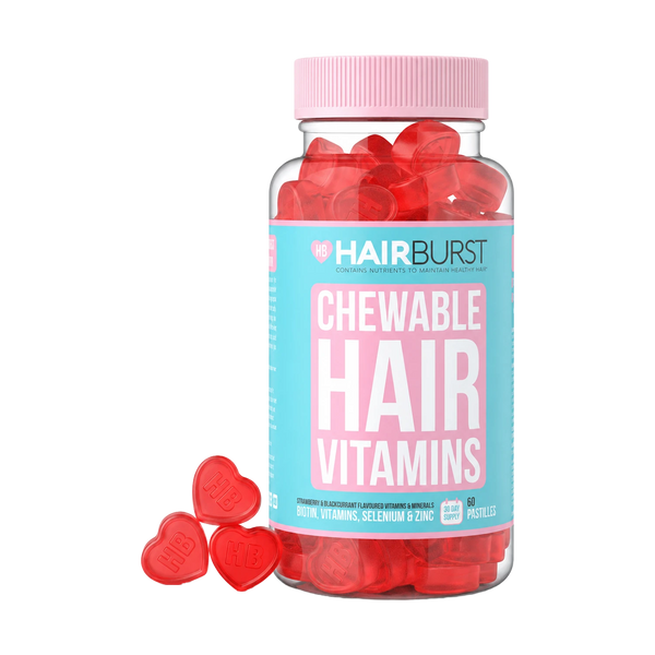 A bottle of HAIRBURST Chewable Hair Vitamins filled with red heart-shaped gummies, with three red heart gummies placed in front on a clean white background.