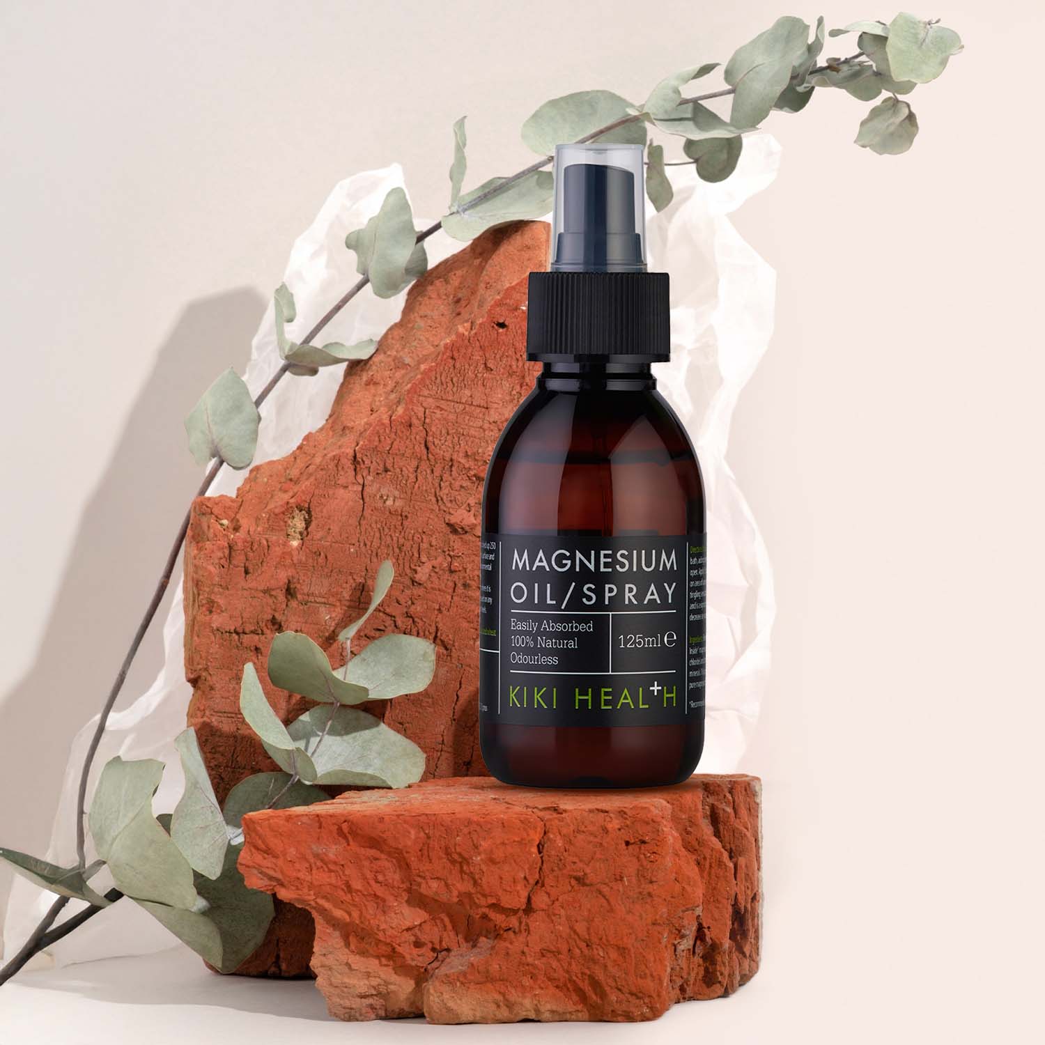 Magnesium oil spray bottle on a natural stone surface with eucalyptus leaves