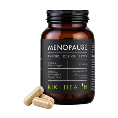 An amber supplement bottle labeled 'MENOPAUSE' by Kiki Health+ with three beige capsules placed in front on a clean white background.