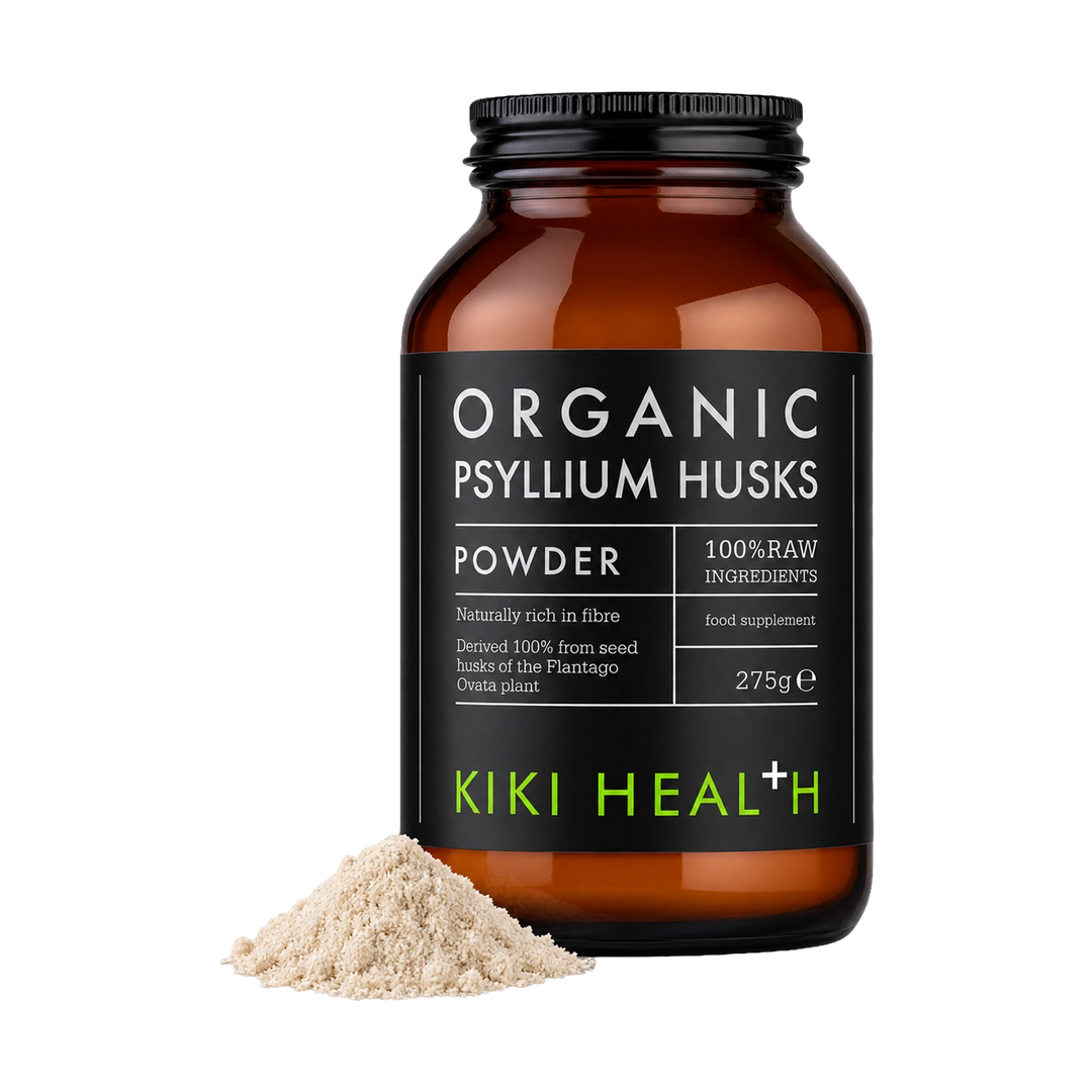 An amber glass jar of Kiki Health Organic Psyllium Husks powder with a black label, shown on a white background with a small pile of the beige powder in front.