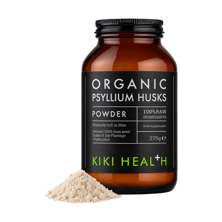 An amber glass jar of Kiki Health Organic Psyllium Husks powder with a black label, shown on a white background with a small pile of the beige powder in front.