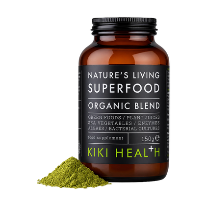 A bottle of Nature's Living Superfood Organic Blend food supplement by Kiki Health+, shown on a white background with a small pile of green powder in front of the bottle.