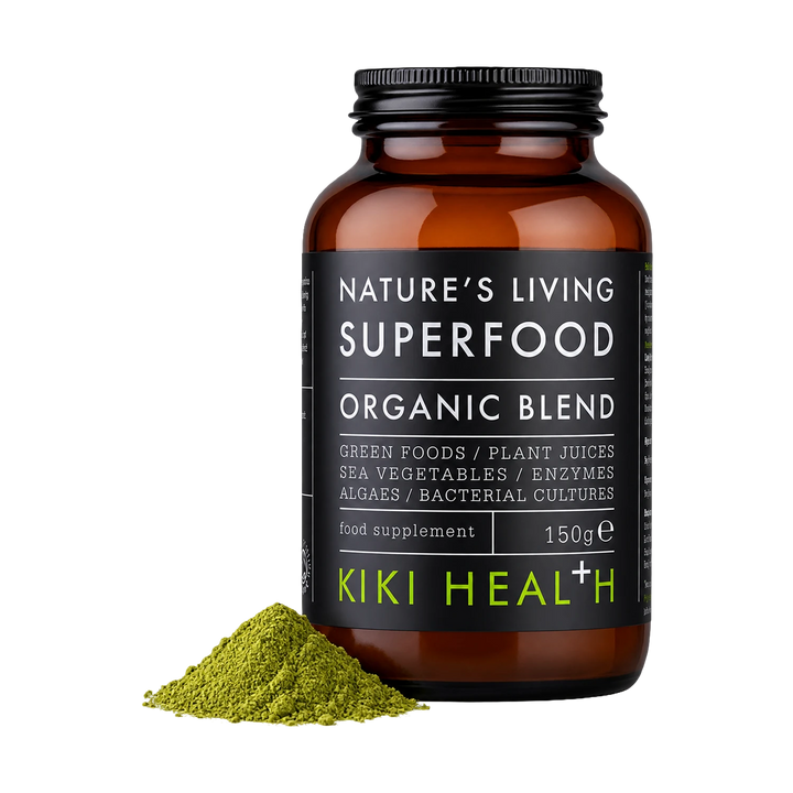 A bottle of Nature's Living Superfood Organic Blend food supplement by Kiki Health+, shown on a white background with a small pile of green powder in front of the bottle.