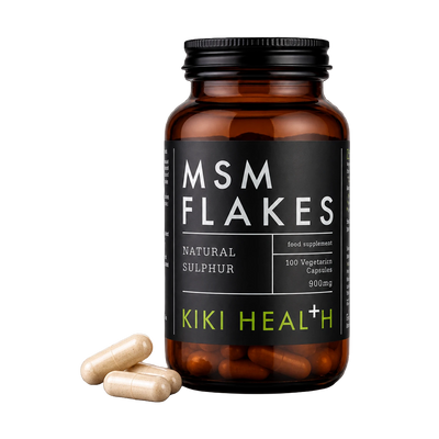 An amber supplement bottle labeled MSM FLAKES by Kiki Health+ with three beige capsules placed in front, on a clean white background.