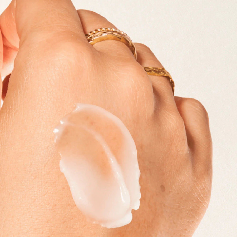 Hand with a small amount of cream on the palm against a neutral background
