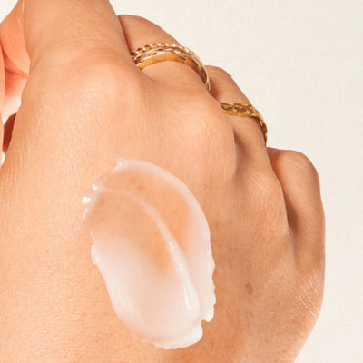 Hand with a small amount of cream on the palm against a neutral background