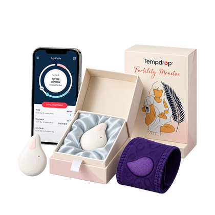 Tempdrop fertility monitor set including a white egg-shaped tracker, a purple cuff, a smartphone app screen, and branded gift box on a white background.