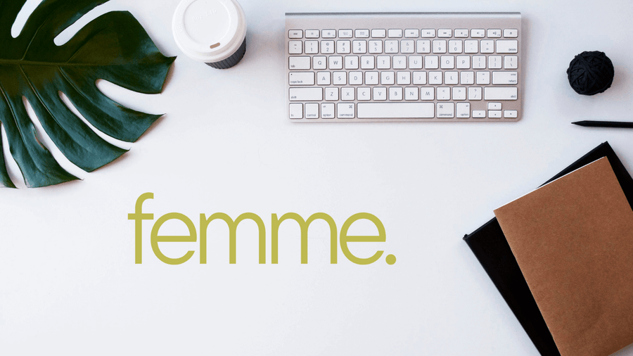 A keyboard, leaf, notebook, pen, and coffee cup arranged on a white surface with femme written below.
