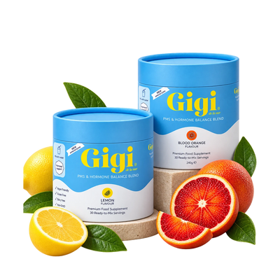 Two Gigi PMS & Hormone Balance Blend containers, lemon and blood orange, styled with fresh fruit on a white background.