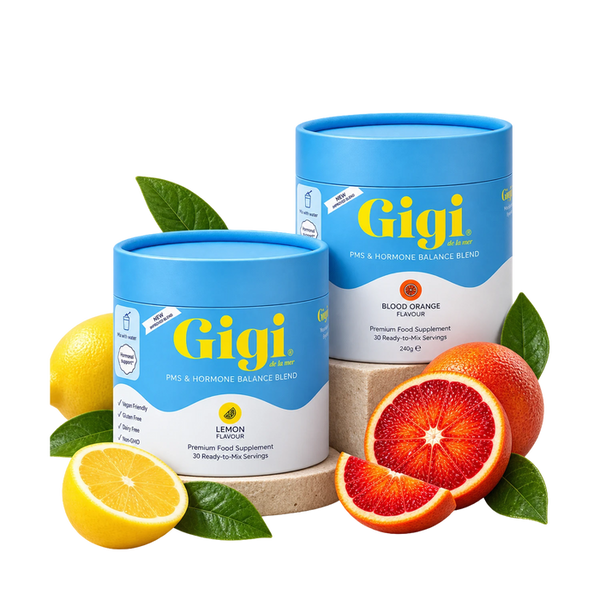Two Gigi PMS & Hormone Balance Blend containers, lemon and blood orange, styled with fresh fruit on a white background.
