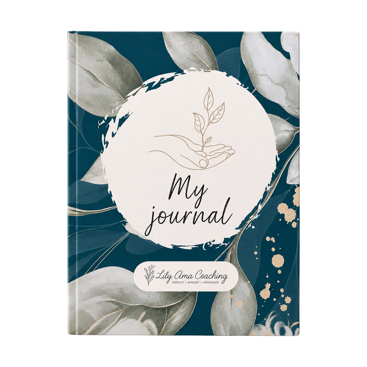 A hardcover journal with a dark teal cover decorated with watercolor-style gray leaves and gold accents. A large white oval in the center features the text 'My journal' with a simple hand holding leaves illustration above it.